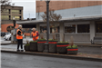Two Women In Orange Vests Working on Potted Plants